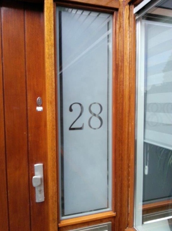 Voordeur met gezandstraald dubbelglas met huisnummer en blanke rand.